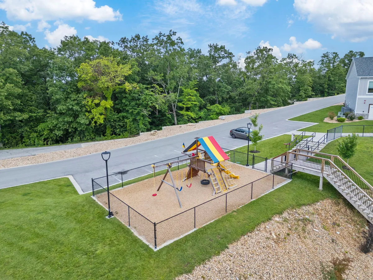 A cheerful and inviting exterior shot of a fenced playground with a colorful play structure, swings, and open green space—perfect for children and family gatherings.